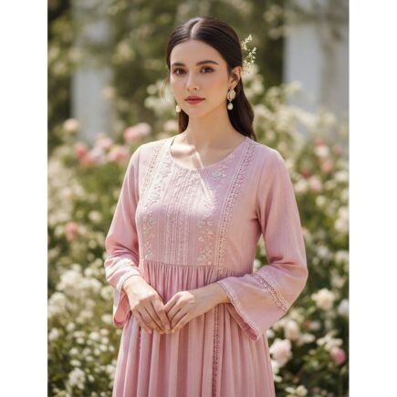 žena v jemných ružových šatách s krajkou stojaca v prírodnom svetle pred rozmazaným kvetinovým pozadím